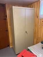 Front view of beige metal storage cabinet with locked double doors, set against wood-paneled basement walls.