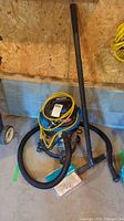 Full view of the Mastervac wet dry vacuum including hose, yellow extension cords wrapped around it, and nozzle attachment on the ground.