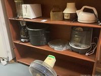 Shelf with small appliances: 2-slice toaster, popcorn popper, canning pot, coffee maker, blender, humidifier, microwave glass plate, and oscillating fan.