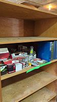 Shelf with assortment of boxes and loose items including spark plugs and maintenance literature