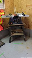 Overall view of the Mastercraft table saw with extension wings and stand in a garage corner.