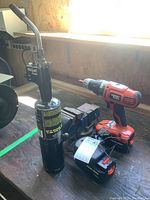 Photo showing Black & Decker cordless drill, battery charger, extra battery, 3 inch bench vise, and Bernzomatic propane torch on workbench under window.