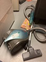 Light blue and gray Bissell Butler Revolution 6700-C canister vacuum on floor with attached hose and power head.