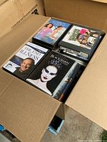 Box with approximately 80-100 DVDs, visible titles include The End of Illness and Black Swan among others.