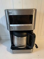 Braun coffee maker exterior showing stainless steel design and control panel with digital display and buttons.