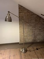 Floor lamp standing next to a wall with exposed brick showing the overall design and condition.