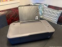 Photo of HP DeskJet F2180 printer with paper input tray extended, showing top angled view