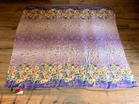 Full view of the scarf laid flat shows floral print and purple background.