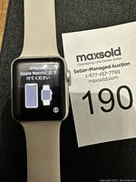 Apple Watch powered on showing a pairing screen with instructions in Japanese and English, with a white silicone band visible