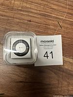 Front view of the 2GB Apple iPod Shuffle in clear plastic packaging showing the circular control pad.