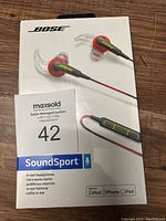 Photo of the front of the Bose SoundSport headphones packaging showing product image, branding, and maxsold auction tag.