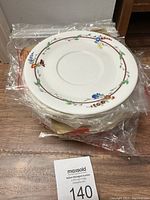 Stack of Royal Doulton bone china saucers with floral rim pattern in original plastic wrap.