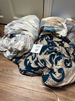 Image of six fabric furniture covers laid on floor, showing various patterns including stripes and large blue floral and leaf prints on beige backgrounds.