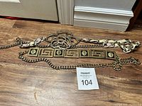Overview of three ladies belts laid out on floor, showing metal, chain, and decorative details