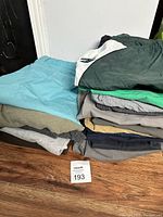 Photo showing stacked men's shorts in multiple colors including light blue, green, gray, and beige, highlighting variety of styles and wear.