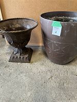 Photo of two planters: a decorative metal planter and a large plastic planter with geometric design.