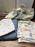 Three twin sheets folded and stacked next to a cream canvas bag with a black and white elephant print on the front and rope handles.