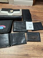 Multiple wallets and phone wallet arranged on floor showing brand logos and wear