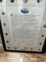 Framed reproduction poster of the Declaration of Independence with circular historical figure images and White House illustration, showing some wear.