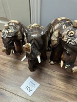 Three carved wooden elephant figurines placed in a row showing size variations and decorative painted details.