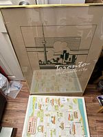 Framed poster showing stylized Toronto skyline and CN Tower in green and beige colors with white text 'Toronto the liveable city.'