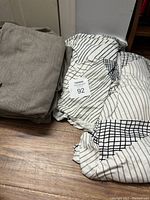 Two stacks of cloth chair covers on a wooden floor, one beige/tan and one white with black grid patterns