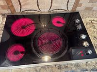 Overview of entire cooktop showing four glowing radiant elements and control knobs