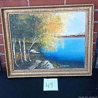 Front view of the framed signed oil painting showing the scenic lakeside scene with trees and rocks, signed K. Majic.