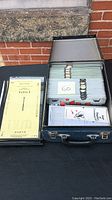 Blue carry case holding multiple sets of Bridge convention cards, numbered tabs visible, yellow score sheets stacked next to it.