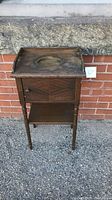 Full view of the mid-century wooden humidor cabinet with four legs, oval cutout on top surface, and closed front door.