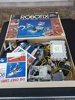 Original box and instruction manuals with various Robotix modular parts and motors visible inside box