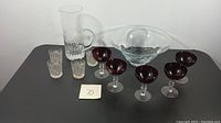 Overview of all items on a table including ruby stem glasses, clear barware, tall handled glass, and large clear bowl