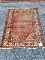 Full view of the rectangular Serabend rug laid on pavement showing the overall pattern and wear