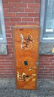 Full view of front side of wooden travel case with painted bear holding a fish artwork