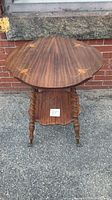 Full view of vintage wooden table showing inlaid top with floral pattern, rope twist legs, and brass claw feet.