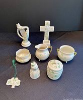 Full collection of eight Belleek porcelain pieces shown on dark fabric background, arranged in two rows.