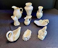 Set of nine vintage Belleek yellow iridescent porcelain pieces arranged on black cloth, clearly showing variety of shapes and details.