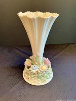 Front view of the ivory-colored Belleek vase with detailed applied porcelain flowers at the base, showing the fluted upper section and scalloped rim.