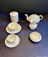 Photo showing the full set arranged on dark cloth, visible are the teapot, creamer, sugar bowl, both teacups with saucers, and jam jar.
