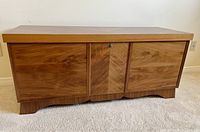 Front view of cedar chest showing three-panel geometric veneer doors and push-button lock