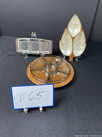 Three different serving trays displayed including a wood and stainless steel compartment tray, a round wooden lazy Susan tray with glass bowls, and a leaf-shaped wooden tray with mother of pearl interior.