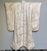 Front view of ivory silk brocade kimono hung flat against wall