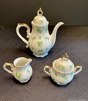 Front view of the three-piece vintage Norcrest china coffee service set showing coffee pot, creamer, and sugar bowl with shamrock design and gold details
