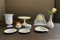 Multiple Wedgwood jasperware items arranged including vases, ashtrays, candy dishes, clock, and lighter.