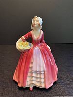 Front view of Royal Doulton Janet figurine showing detailed face, bonnet, and basket of flowers