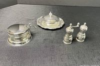 Photo showing the Viking plate glass butter dish with silver tray and lid on the left, salt shaker and pepper mill on the right, on a dark fabric background.