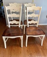 Front view of four chairs showing white frames and cherry seats