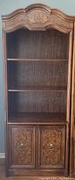 Front view of the full bookcase showing upper shelving, lower cabinet doors with wood veneer panels, and decorative crown molding.