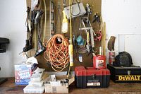 Overall assortment of carpentry tools and extension cords on pegboard and table.