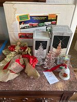 Photo showing Santa's Musical Express train set box with other Christmas decorations on a table including crystal glass trees, an angel door hanger, bell ornament, and plane carousel ornament.